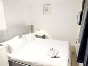 a bedroom with a white bed with a book on it at Family Friendly 3BR Haven in Northolt with Parking in South Ruislip Station