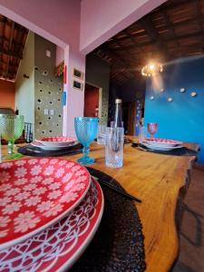 a wooden table with plates and glasses on top of it at Casa Cores da Redonda! in Icapuí +25 photos