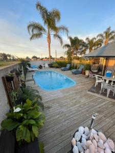 Un patio trasero con piscina y terraza de madera. en Casa ampla com área gourmet e piscina, en Capão da Canoa