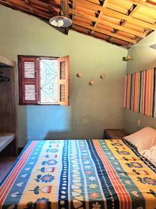 a bedroom with a colorful bed with a window at Casa Cores da Redonda! in Icapuí