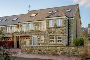 una antigua casa de piedra con balcón. en Twin Palms No 2, en North Sunderland