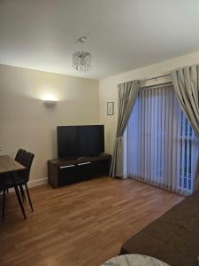 un salon avec une télévision à écran plat et une table dans l'établissement Bargh Apartment - 2 bed 2 bath, modern comfort, à Balderton