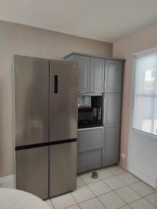 een keuken met een roestvrijstalen koelkast en een magnetron bij Oléron proche plage pour vacances ou travail in Dolus d'Oléron