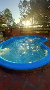 a large blue pool with the sun in the background at Cabañas El Paso in Villa del Dique