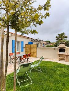 een patio met stoelen en een tafel in de tuin bij Oléron proche plage pour vacances ou travail in Dolus d'Oléron