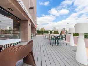 a deck with tables and chairs on a building at Ibis Alcala de Henares La Garena in Alcalá de Henares