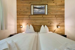 2 letti bianchi in una camera con pareti in legno di Apartments Enzian a Rauris