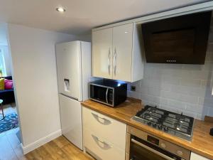a kitchen with white cabinets and a microwave at Pippin Cottage central Bewdley 2 parking spaces in Bewdley +6 photos