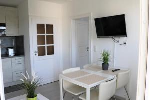 a white kitchen with a table and a tv on the wall at Nordsee 03 in Cuxhaven