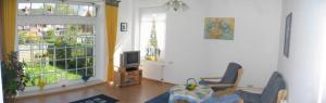 a living room with a couch and a tv and two windows at Badehausallee 20 Wohnung 1 in Cuxhaven