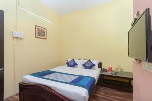 ein Schlafzimmer mit einem Bett und einem Flachbildfernseher in der Unterkunft Hotel O B Square Homes in Singānallūr