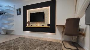 a room with a chair and a television on a wall at Zentral wohnen in der Mainzer City in Mainz