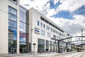 un gran edificio blanco con un tren delante en ibis budget Dresden City, en Dresden