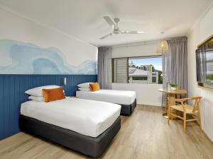 a hotel room with two beds and a table at Mercure Cairns in Cairns