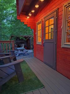 a porch of a red house with a bench and a door at Shelley' Bay Bunkie 1 in Sharbot Lake