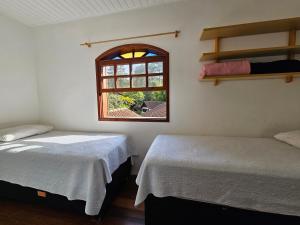 two beds in a room with a window at Casa Incrível em Nova Friburgo - Espaço Humedica in Nova Friburgo +108 photos