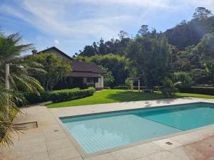 a swimming pool in front of a house at Casa Incrível em Nova Friburgo - Espaço Humedica in Nova Friburgo