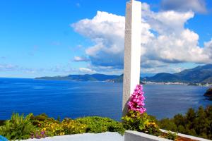 a white obelisk with flowers in front of the water at Blue Mediterranean Apartments in Sveti Stefan
