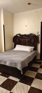 a bed with a wooden headboard in a room at Family apartment LUXOR in Jazīrat al ‘Awwāmīyah