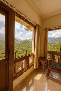 a room with a window with a chair and a view at The Mayur Captain Grand Resort kasauli in Kasauli +32 photos