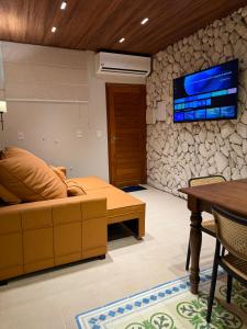 a living room with a couch and a tv on a stone wall at Ilha Bela Alter do chão - Apartment 2 suites in Santarém