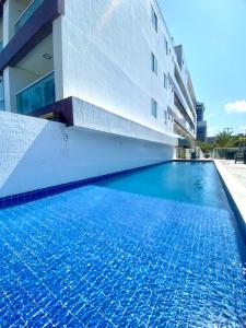 a swimming pool in front of a building at Flamboyant Oceania Flats in João Pessoa