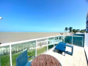 a deck with a table and chairs and the beach at Flamboyant Oceania Flats in João Pessoa