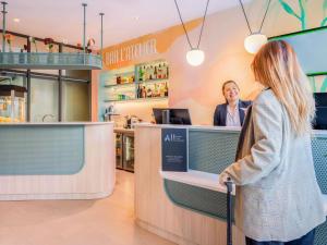Una mujer parada en un mostrador de una tienda en ibis Styles Paris Porte d'Orléans, en Montrouge