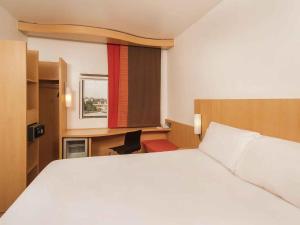 a hotel room with a large bed and a desk at Ibis Lagos Ikeja in Ikeja