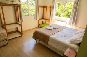 a bedroom with a bed and two windows at Pousada Casa do Reiki in Rancho Queimado