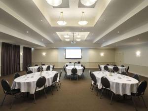 a conference room with white tables and chairs and a screen at ibis Styles Tamworth in Tamworth +37 photos