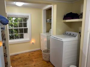 a laundry room with a washer and a window at Quaco Cottages-The Shipbuilder's Summer Kitchen in Saint Martins
