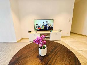 ルクセンブルクにあるElegant 3BR Retreat with terraces&parkingのリビングルーム(テレビ、テーブルの花付)