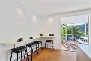 a white kitchen with a counter and stools at Deluxe Queen Room at Wolfe Street in Whangarei