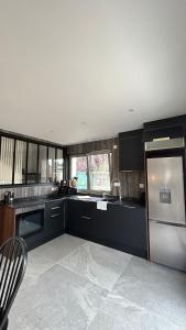 cocina con armarios negros y nevera de acero inoxidable en Villa Pauline 1, en Créteil