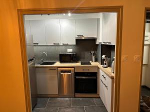 eine Küche mit weißen Schränken und einer Spüle und einer Mikrowelle in der Unterkunft Appartement au pied des pistes Serre chevalier in La Salle Les Alpes