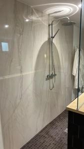 y baño con ducha y pared de mármol. en Villa Pauline 1, en Créteil