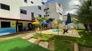 a building with a pool and a patio with umbrellas at Pousada Lá na Praia Maragogi in Maragogi