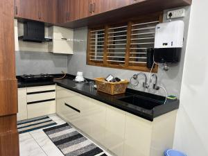 マイソールにあるSamruddhi Hill View Homestayのキッチン(白いキャビネット、黒いカウンタートップ付) +10枚の写真