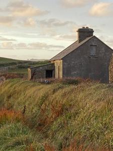 an old building sitting on top of a grassy hill at Journey's End B&B in Milltown Malbay