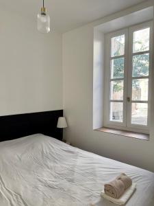 a white bedroom with a bed and a window at Séjour de charme au cœur de Carcassonne in Carcassonne