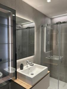 ein Badezimmer mit Waschbecken und Glasdusche in der Unterkunft Exclusive flat on Lake Como with panoramic views in Como