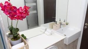Un baño con lavabo y espejo y flores rosas. en 2 Bed Deluxe Apt City Centre, Long stay, en Mánchester