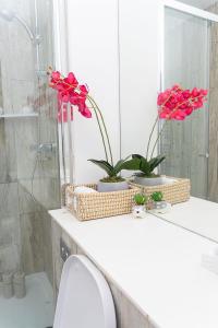 Un baño con dos flores rojas sobre un mostrador. en 2 Bed Deluxe Apt City Centre, Long stay, en Mánchester