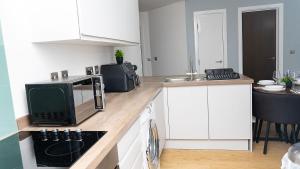 Una cocina con gabinetes blancos y un microondas. en 2 Bed Deluxe Apt City Centre, Long stay, en Mánchester 20 fotos más