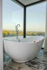 bañera blanca en una habitación con ventana grande en Enigma - Nature & Water Hotel en São Teotónio