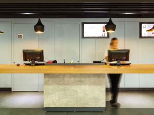a person walking past a desk with two computer monitors at ibis Cascavel in Cascavel