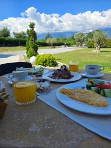 a table with plates of food and glasses of beer at Olympus Pantheon Luxury Rooms in Plaka Litochorou