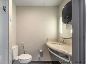 um banheiro com vaso sanitário, pia e espelho em ibis Curitiba Shopping em Curitiba mais 116 fotografias