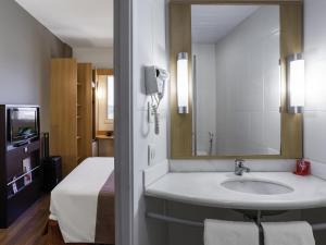 a bathroom with a sink and a bed and a mirror at ibis Jaboticabal in Jabuticabal +116 photos